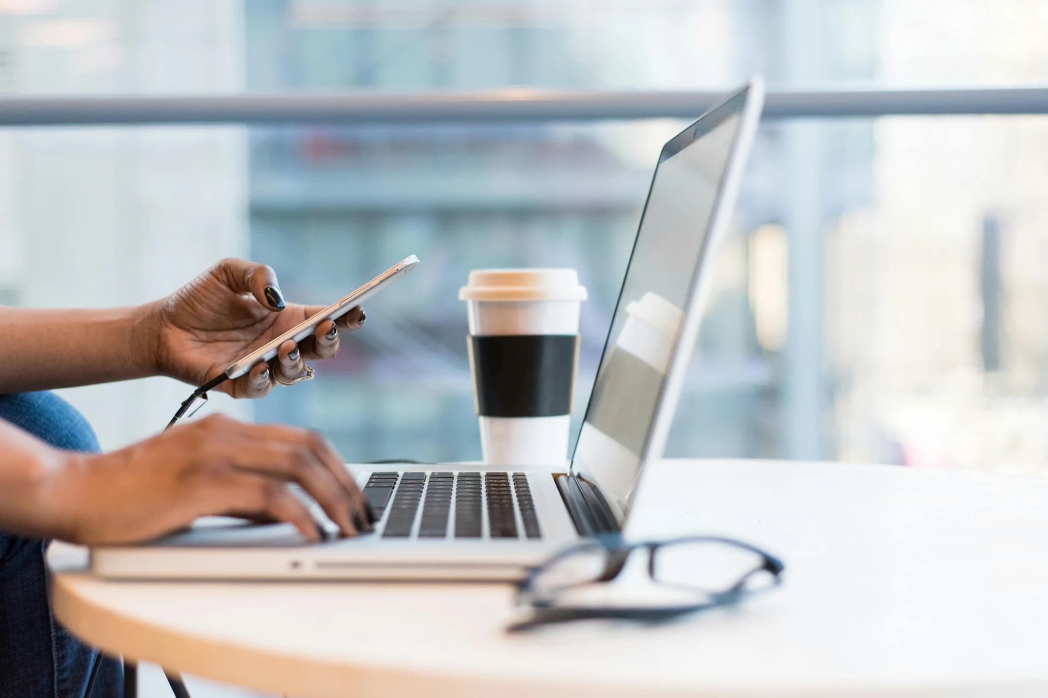 Woman's hand holding a phone in front of a laptop